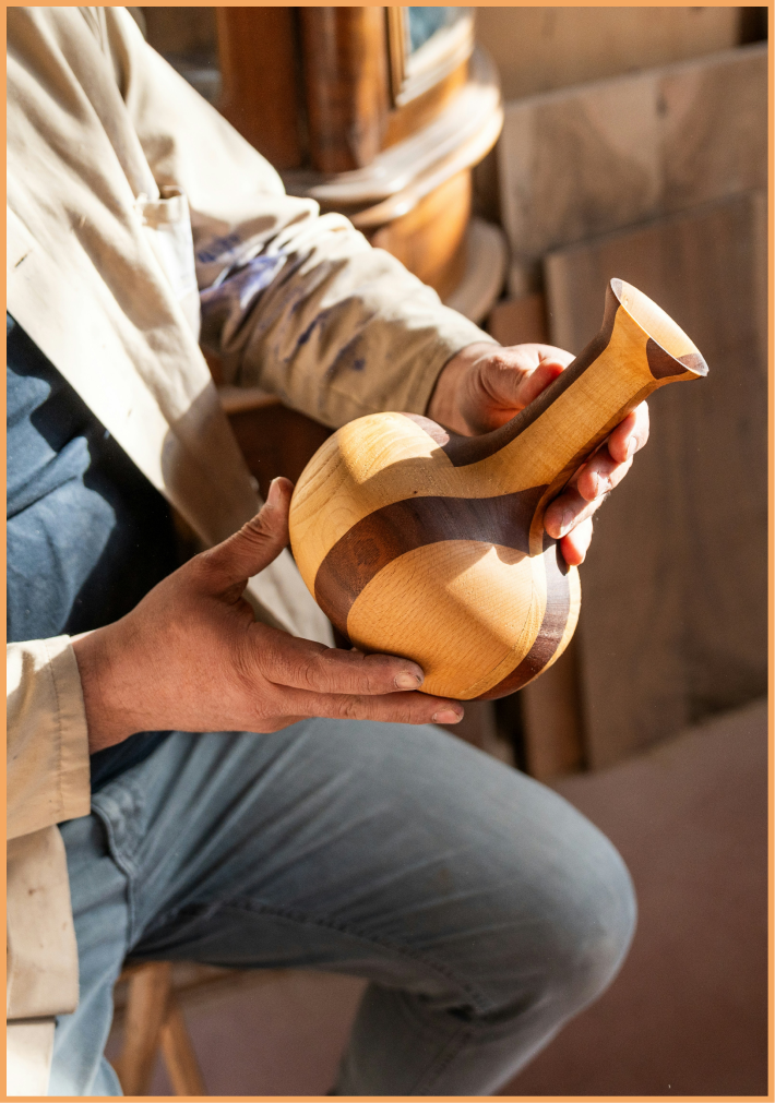 main looking at vase made of wood